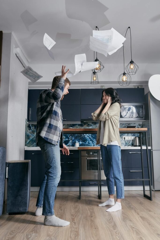 Frustración por facturas eléctricas injustas — Reclama Energía te ayuda a resolverlo Pareja frustrada lanzando facturas al aire en la cocina por cobros injustos de luz